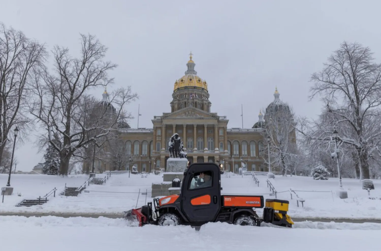 Workers remove snow from the sidewalk outside of the Iowa State Capitol Building after a snowstorm left several inches of snow in Des Moines, Iowa, US, January 9, 2024. REUTERS/Alyssa Pointer/File Photo
