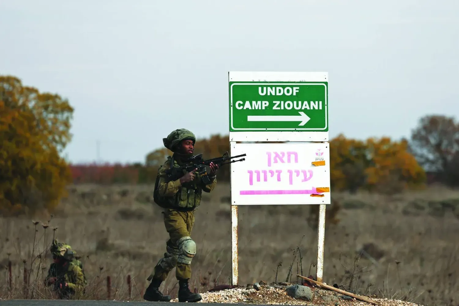 Golan Tepeleri'nde bulunan Kuneytra geçiş noktası yakınlarındaki Birleşmiş Milletler Ateşkes Gözlem Gücü (UNDOF) karakolunda bir tabelanın yanında duran iki İsrail askeri. (EPA)