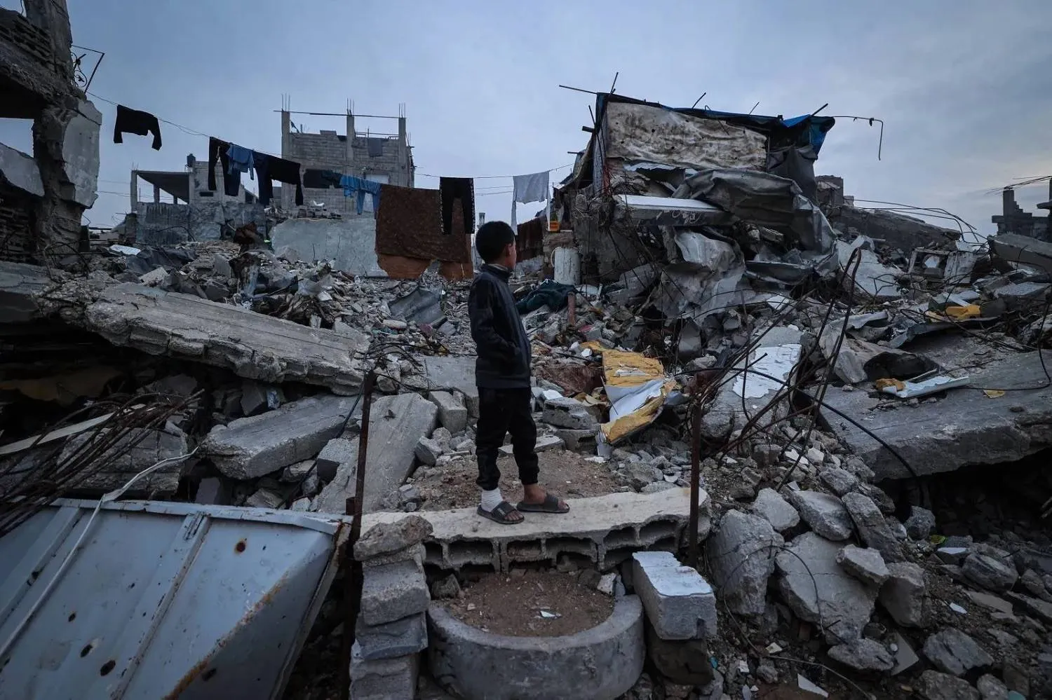 A displaced Palestinian child stands atop the rubble of destroyed buildings in the Al-Bureij refugee camp in central Gaza (AFP)