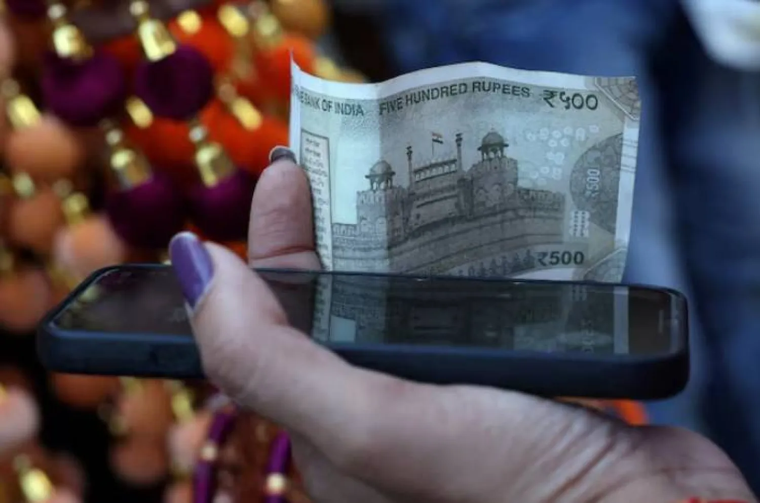 امرأة تمسك بورقة نقدية فئة 500 روبية في الأحياء القديمة لدلهي (رويترز)