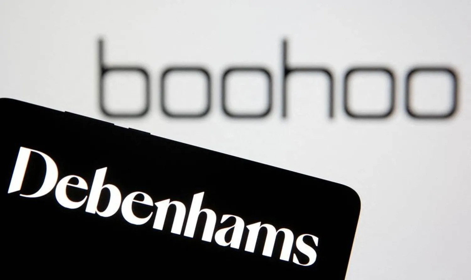 Debenhams logo is seen on smartphone in front of a displayed Boohoo logo in this illustration taken January 25, 2021. (Reuters) 