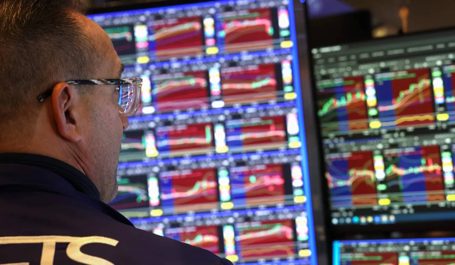 متداول يراقب شاشة تعرض مؤشرات الأسهم في بورصة نيويورك (رويترز)