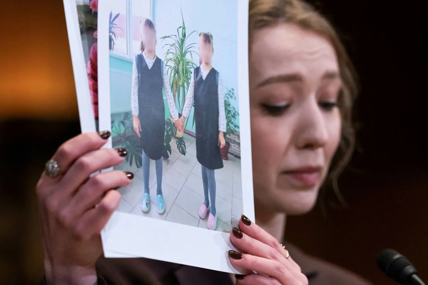 كاترينا راتشفسكا الخبيرة القانونية في «المركز الإقليمي لحقوق الإنسان» تحمل صوراً تقول إنها تُظهر أطفالاً أوكرانيين مختطفين أثناء إدلائها بشهادتها أمام لجنة في مجلس الشيوخ الأميركي يوم 3 ديسمبر 2025 (رويترز)