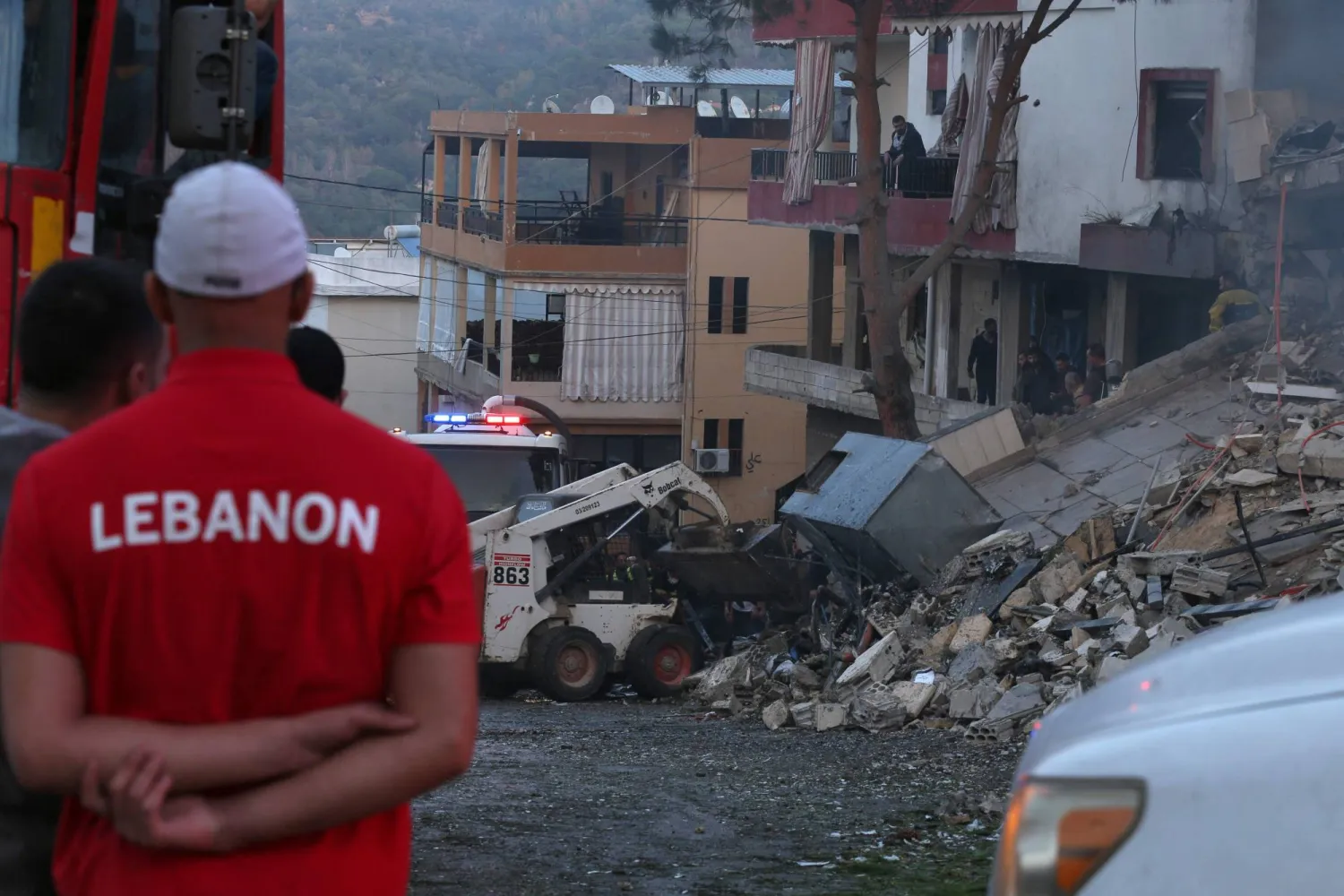 لبنانيون يشاهدون عمليات البحث عن ناجين في موقع غارة إسرائيلية استهدفت قرية جباع جنوب لبنان أمس (أ.ف.ب)
