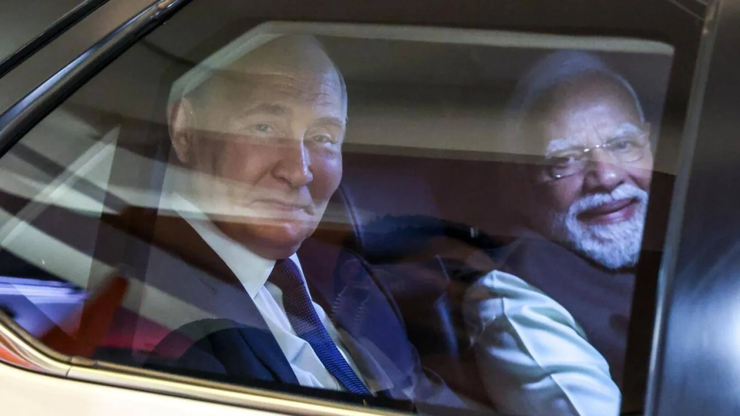 In this pool photograph distributed by the Russian state agency Sputnik, Russia's President Vladimir Putin and Indian Prime Minister Narendra Modi look out from a car prior to an informal dinner at Modi's residence. Alexander KAZAKOV / POOL/AFP 