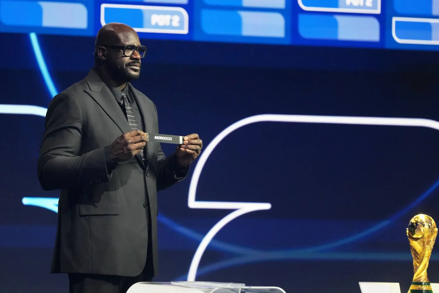 أونيل نجم السلة المعتزل لحظة عرضه بطاقة المغرب خلال مراسم القرعة (أ.ب)