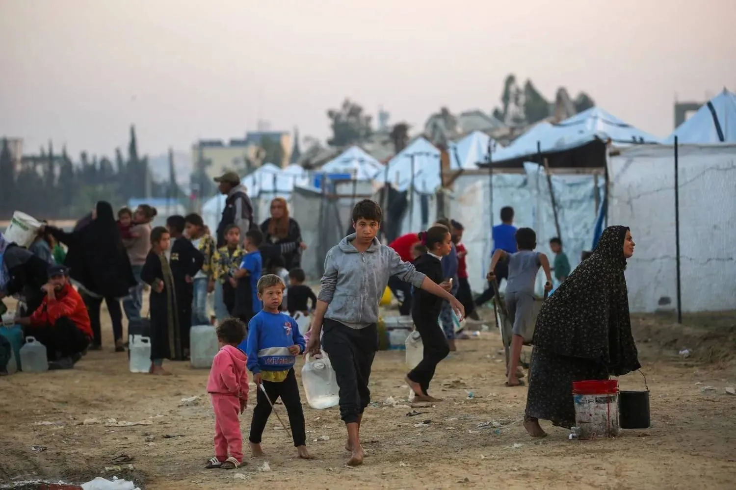 Palestinians fill water containers at the Nuseirat camp for displaced families in central Gaza (AFP)