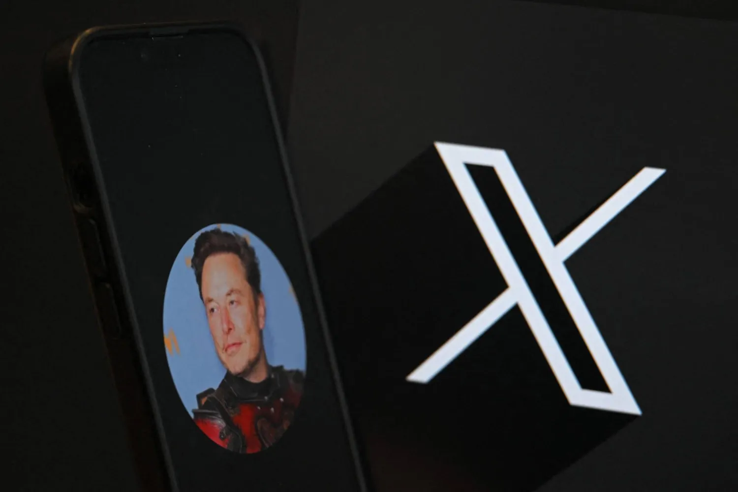 (FILES) This illustration photograph shows the logo of social network X (formerly Twitter) and a photograph of CEO of social network X, Elon Musk displayed on a smartphone in Brussels on September 27, 2024. (Photo by Nicolas TUCAT / AFP)