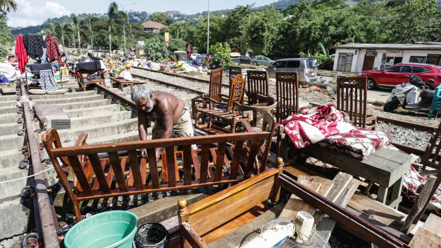 A Sri Lankan flood victim sorts out his belongings by railway tracks in Kandy. The authorities have issued fresh landslide warnings as monsoon storms make hillsides unstable. AFP
