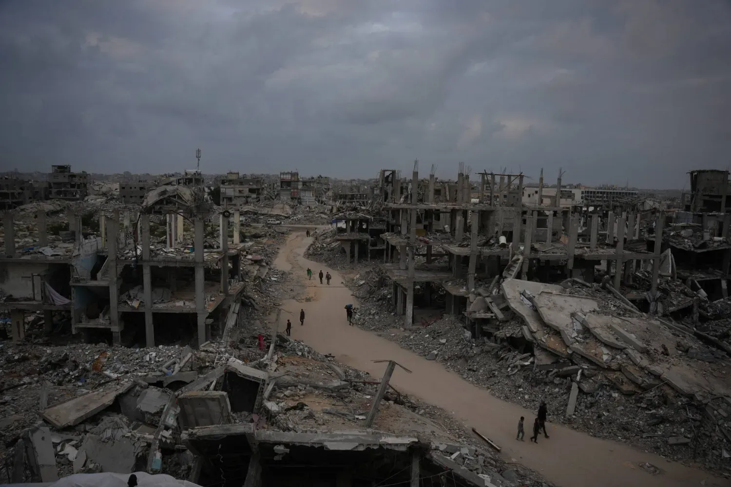 Filistinliler, Gazze Şeridi'nin kuzeyindeki Cebaliye'de, İsrail'in Gazze Şeridi'ne yönelik savaşında yıkılan binaların arasında sokakta yürüyor (AP)