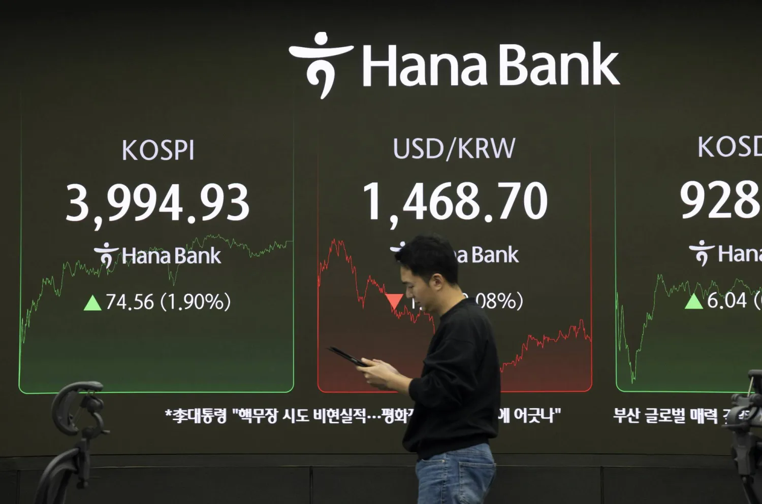متداول يمر أمام شاشات تعرض مؤشر «كوسبي» ببنك هانا في سيول (إ.ب.أ)