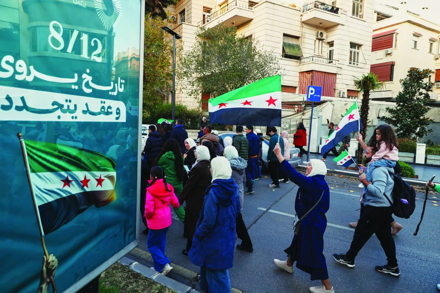 
سوريون يلوحون بأعلام بلدهم وهم يشاركون في الاحتفالات بسقوط نظام بشار الأسد في دمشق أمس (أ.ب)