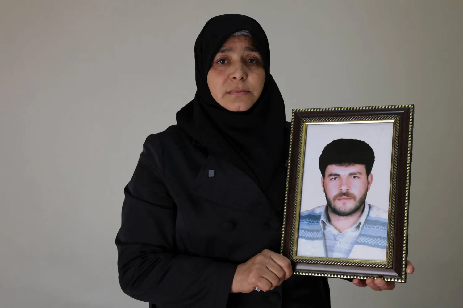 Amina Beqai holds a photo of her husband, who went missing after he was arrested by security forces under the rule of ousted President Bashar al-Assad, in Damascus, Syria, November 23, 2025. (Reuters)