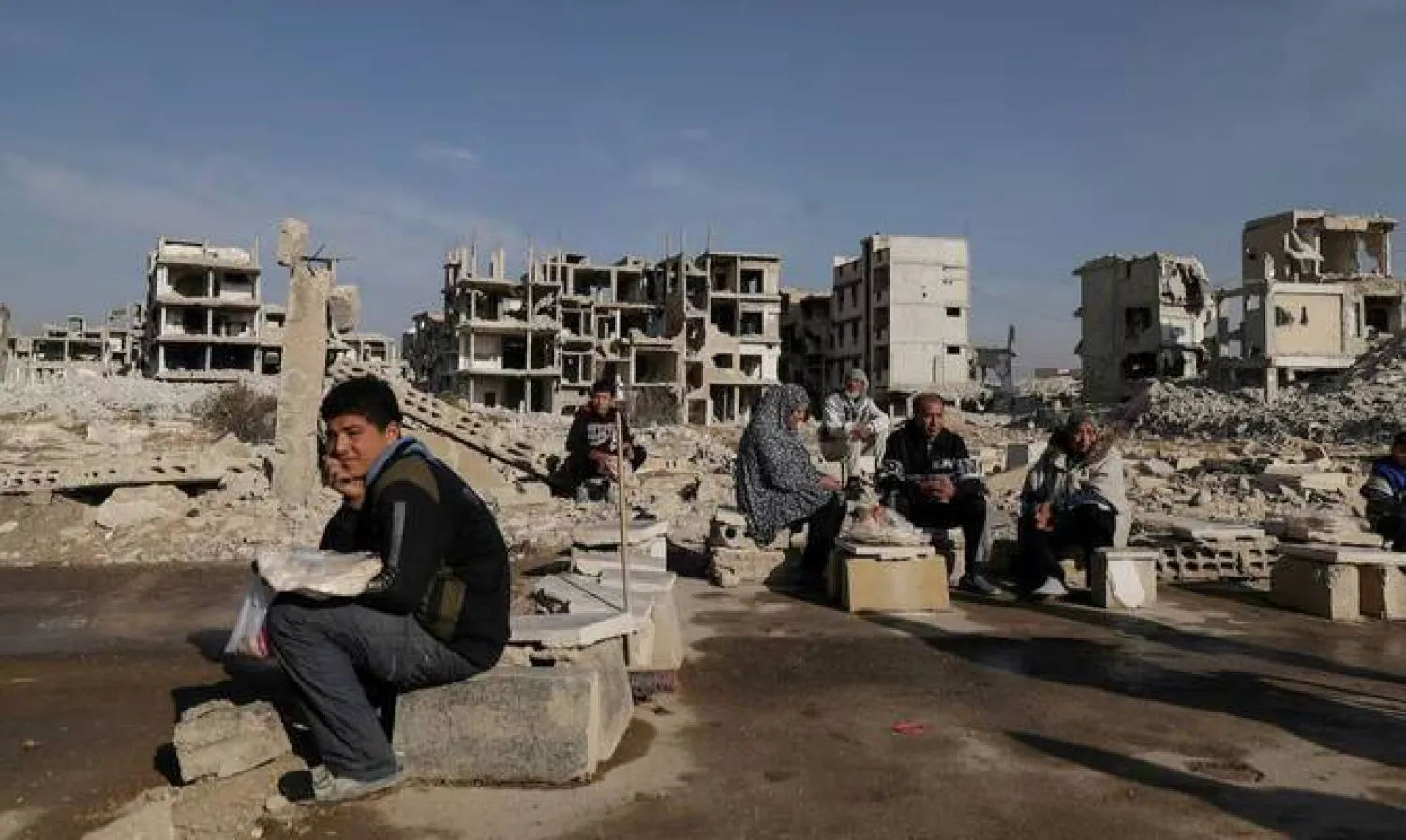 People sit after receiving bread from Ecir Kapici, Turkish humanitarian NGO at Al-Yarmouk Palestinian refugee camp, after Syria's Bashar Al-Assad was ousted, in Damascus, Syria, December 20 , 2024. (Reuters)
