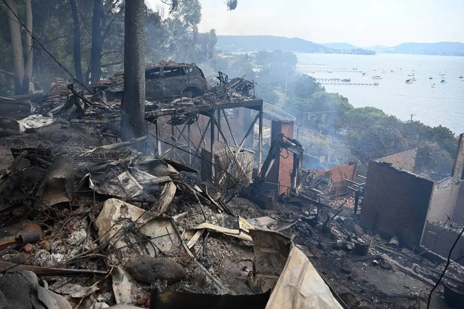Ruins of buildings and a car smolder after a wildfire destroyed houses in Koolewong, Australia, Saturday, Dec. 6, 2025. (Dan Himbrechts/AAP Image via AP)