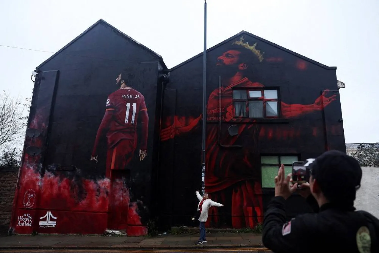 A man photographs his wife next to a mural of Egypt soccer player Mohamed Salah, who joined Liverpool FC as a winger in 2017, painted by artist John Culshaw, in Liverpool, Britain, December 7, 2025. (Reuters)