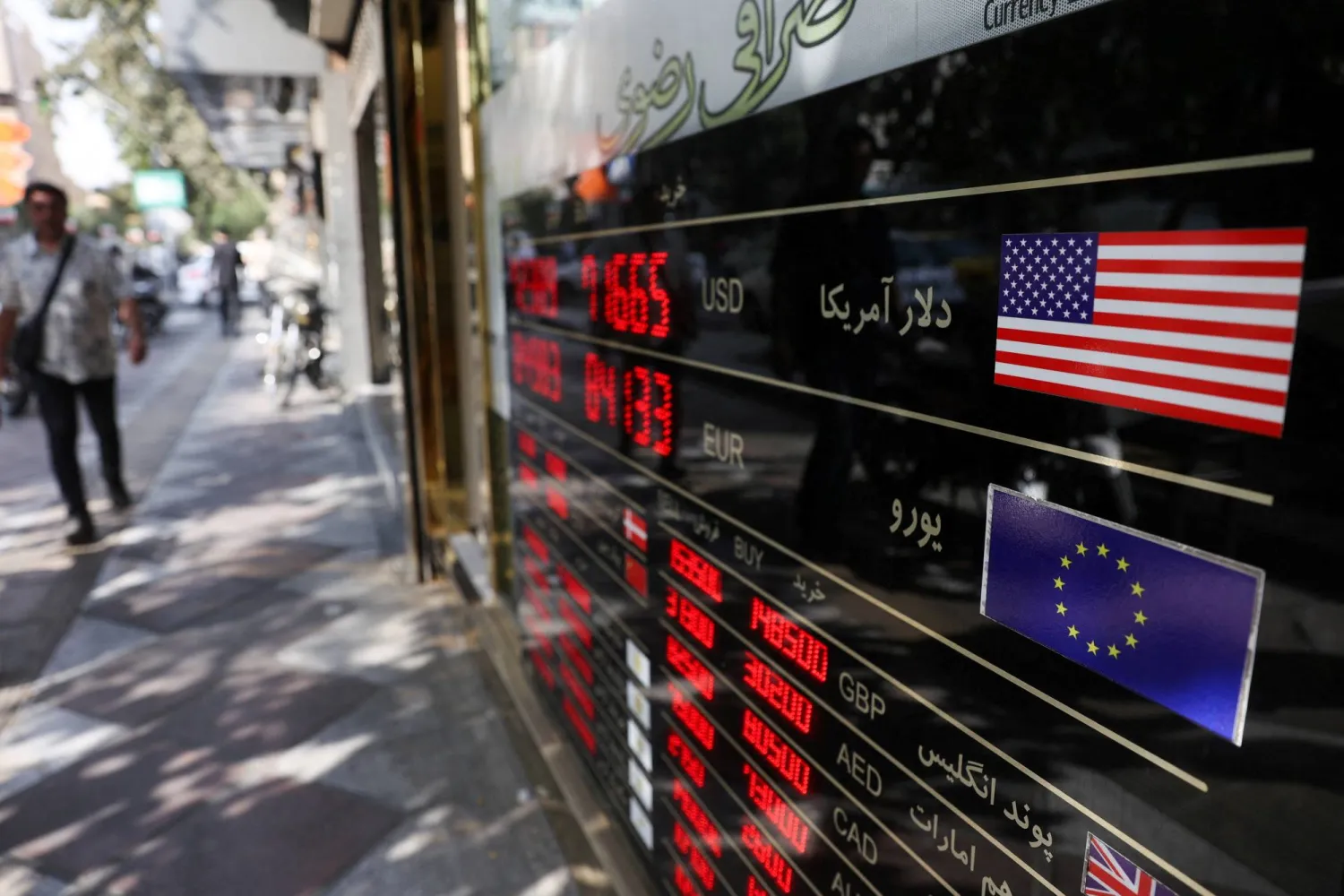 FILE PHOTO: People walk past a sign at a currency exchange as the value of the Iranian Rial drops, in Tehran, Iran, October 5, 2025. Majid Asgaripour/WANA (West Asia News Agency) via REUTERS