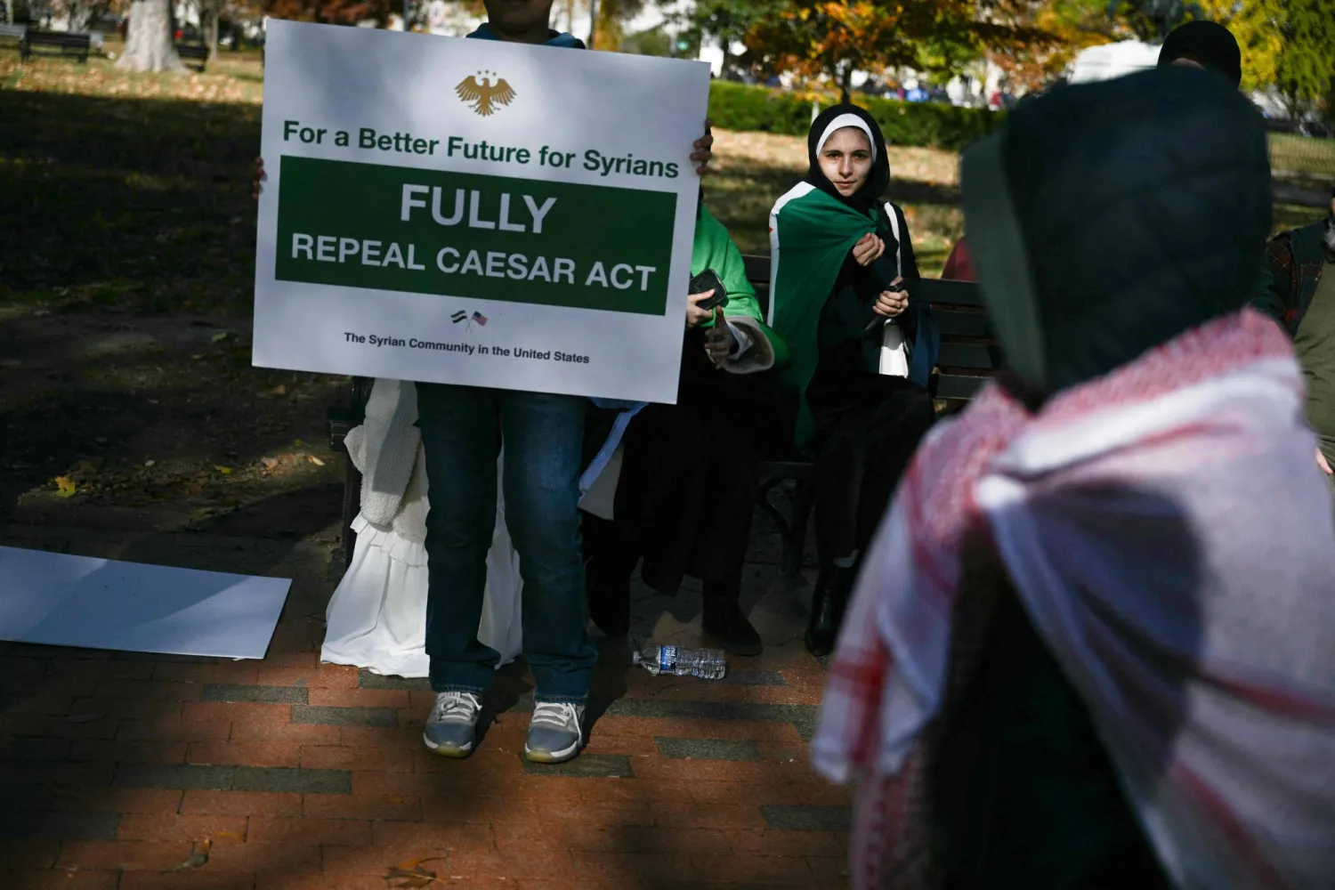 لافتة تدعو إلى إلغاء قانون قيصر يحملها متظاهرون أمام البيت الأبيض في 10 نوفمبر الماضي (أ.ف.ب)