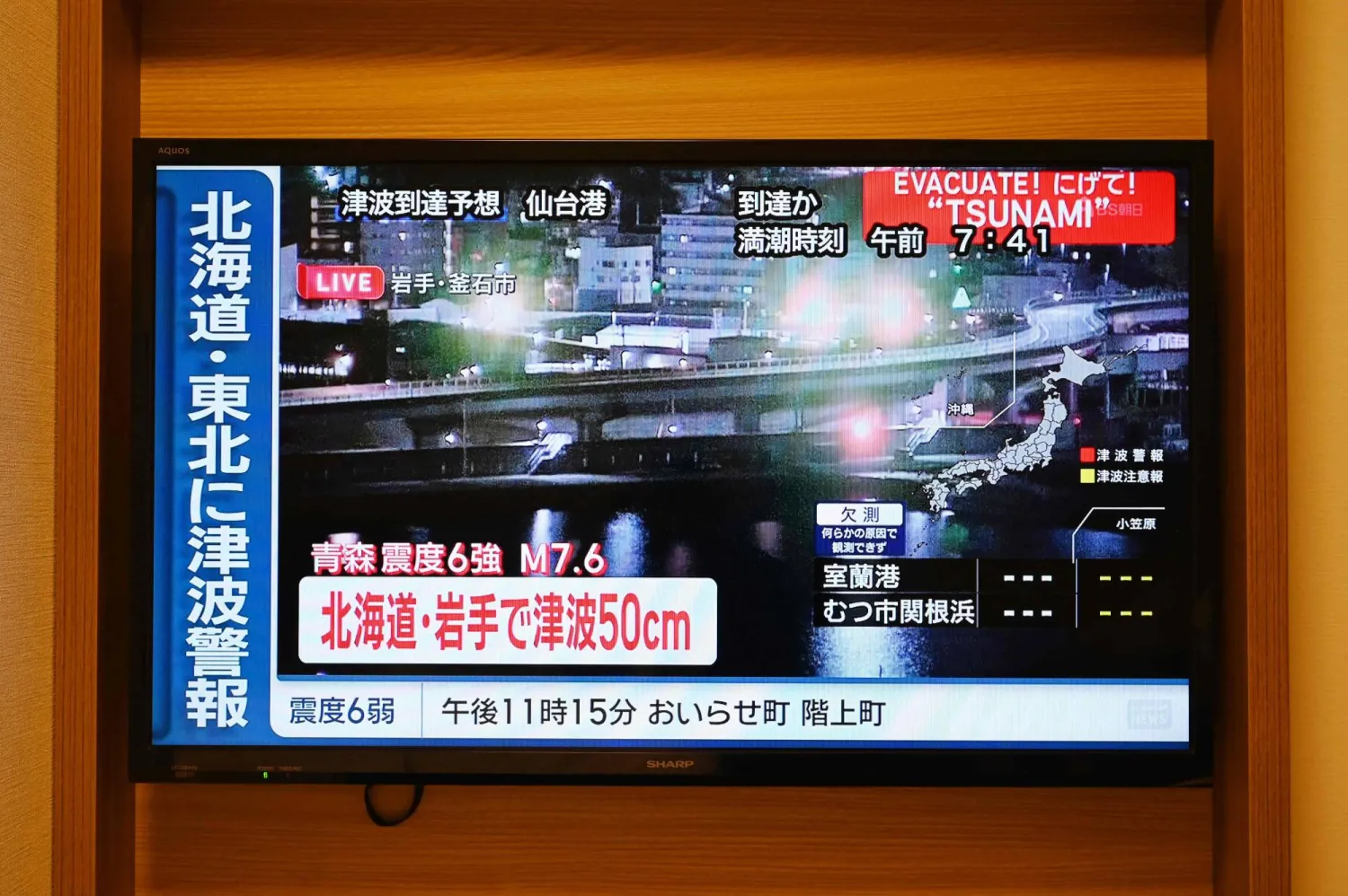 A tsunami warning flashes over live footage of a waterfront area, on a television screen in Sapporo, in Japan's northern Hokkaido prefecture on December 9, 2025. (AFP)