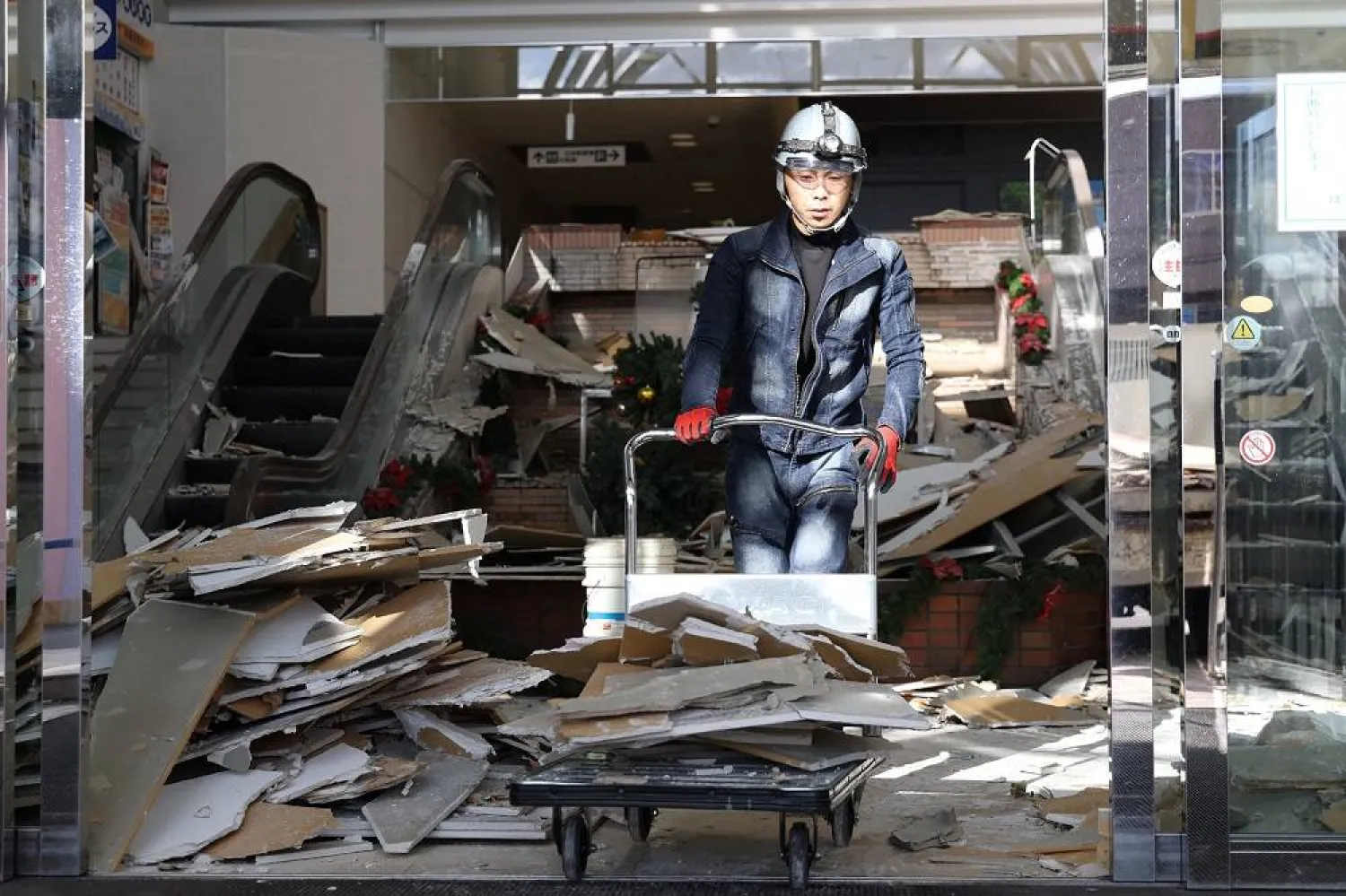 A worker clears debris at a shopping center damaged by the earthquake in Hachinohe City, Aomori Prefecture on December 9, 2025. (Jiji Press/AFP) 