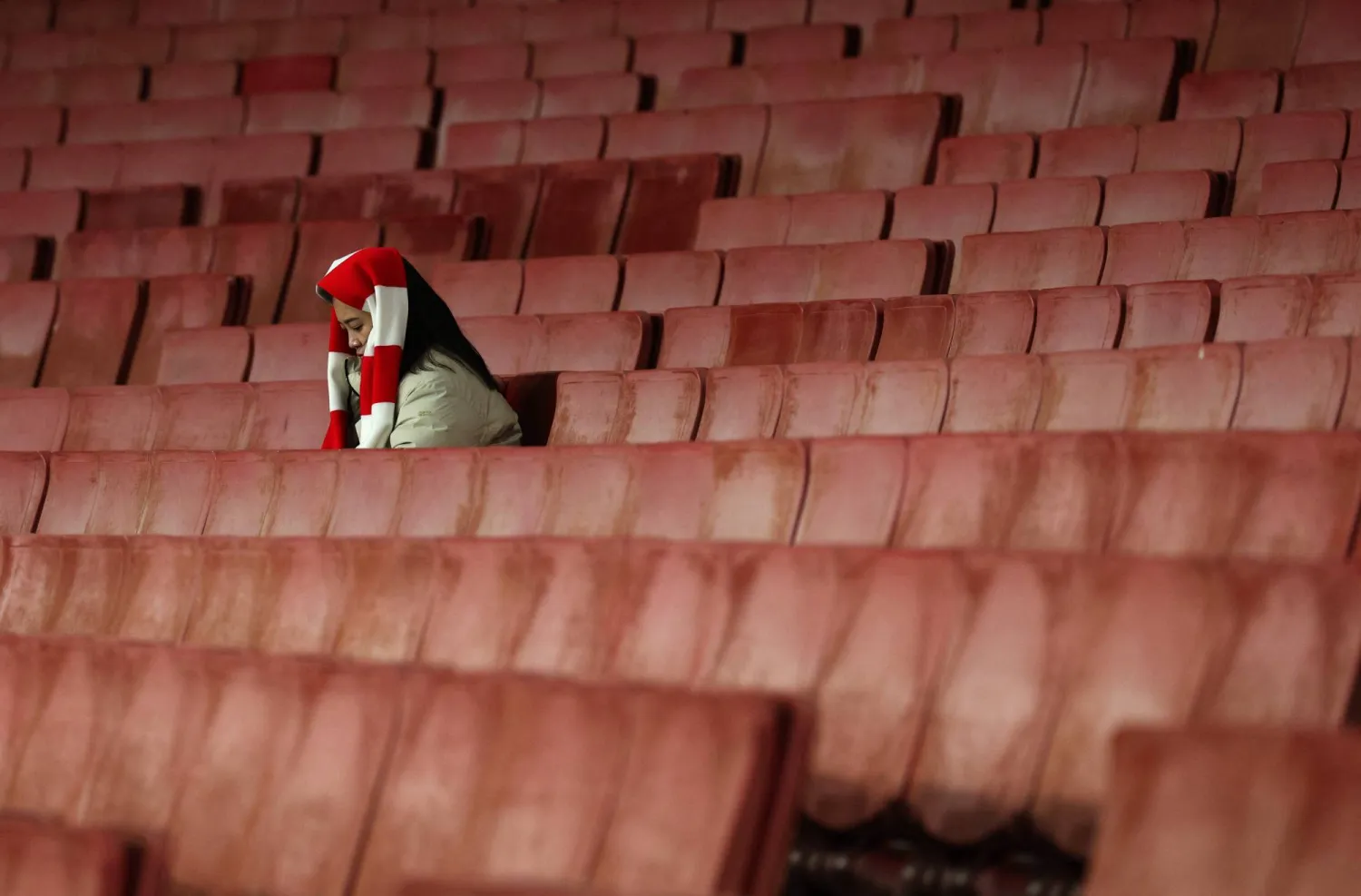A lone Arsenal fan sits in the stands ahead of the English Premier League football match between Arsenal and Brentford at the Emirates Stadium in London on December 3, 2025. (AFP)