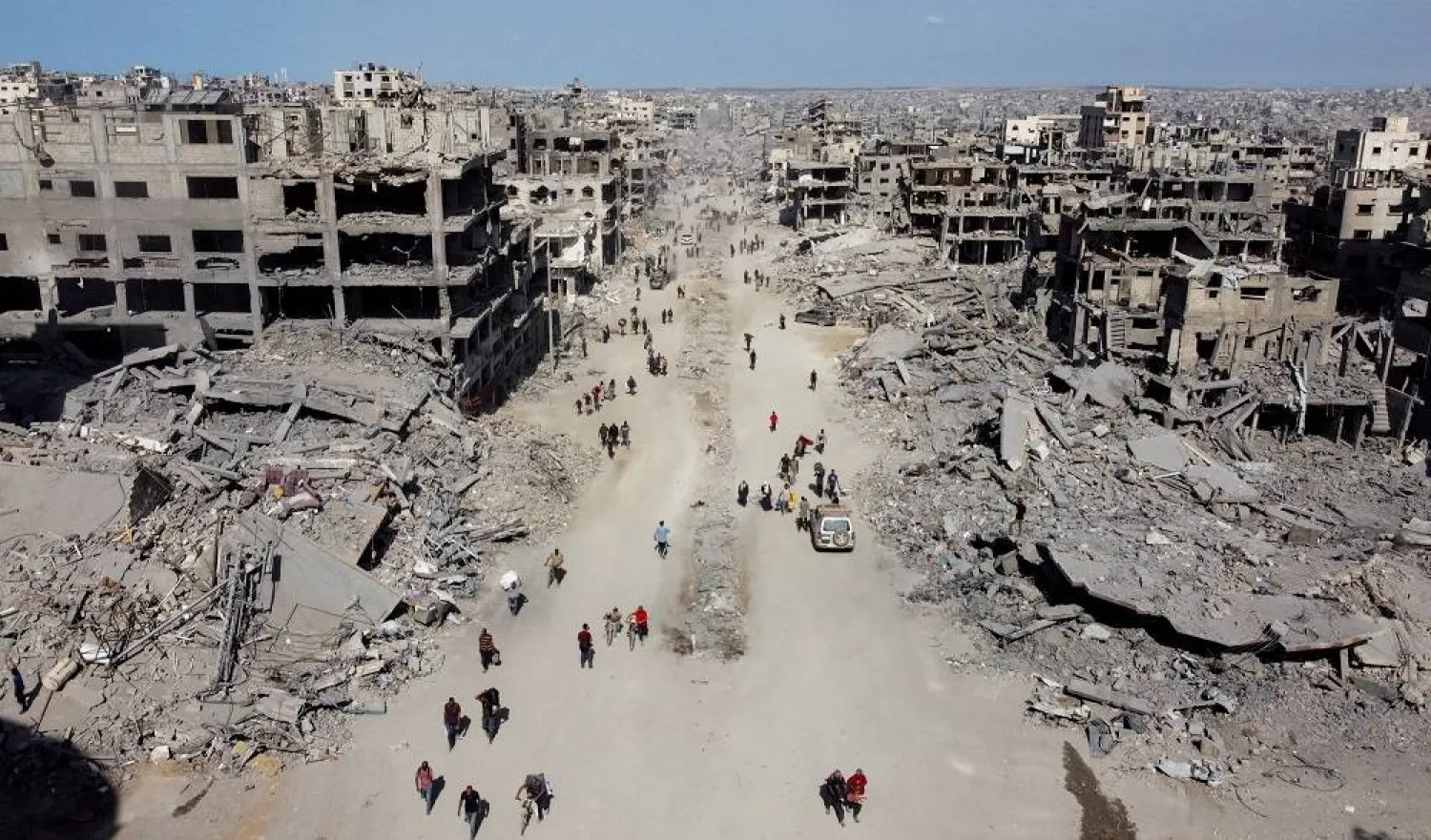 A drone view shows Palestinians walking past the rubble, following Israeli forces' withdrawal from the area, amid a ceasefire between Israel and Hamas in Gaza, in Gaza City, October 11, 2025. (Reuters) 