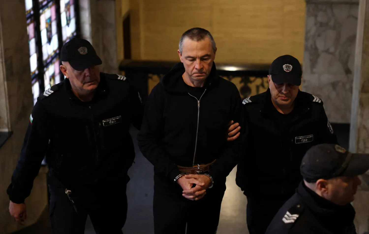 عنصران من الشرطة البلغارية يقودان الروسي إيغور غريتشوشكين إلى قاعة المحكمة في بلغاريا للاستماع إلى إفادته (رويترز)
