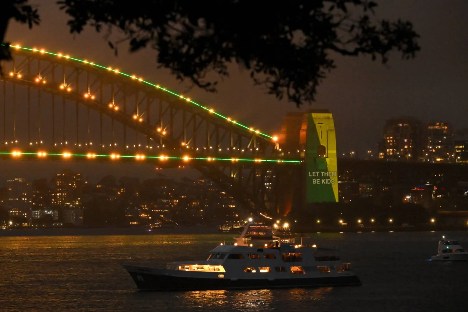 رفع شعار «دَعُوهم يبقوا أطفالاً» ضمن حملة تقييد استخدام التواصل الاجتماعي للقُصّر على جسر ميناء سيدني في أستراليا يوم 10 ديسمبر (إ.ب.أ)