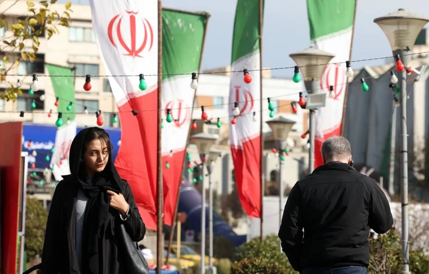 Iranians walk past Iran's national flag on a street in Tehran, Iran, 10 December 2025. (EPA)