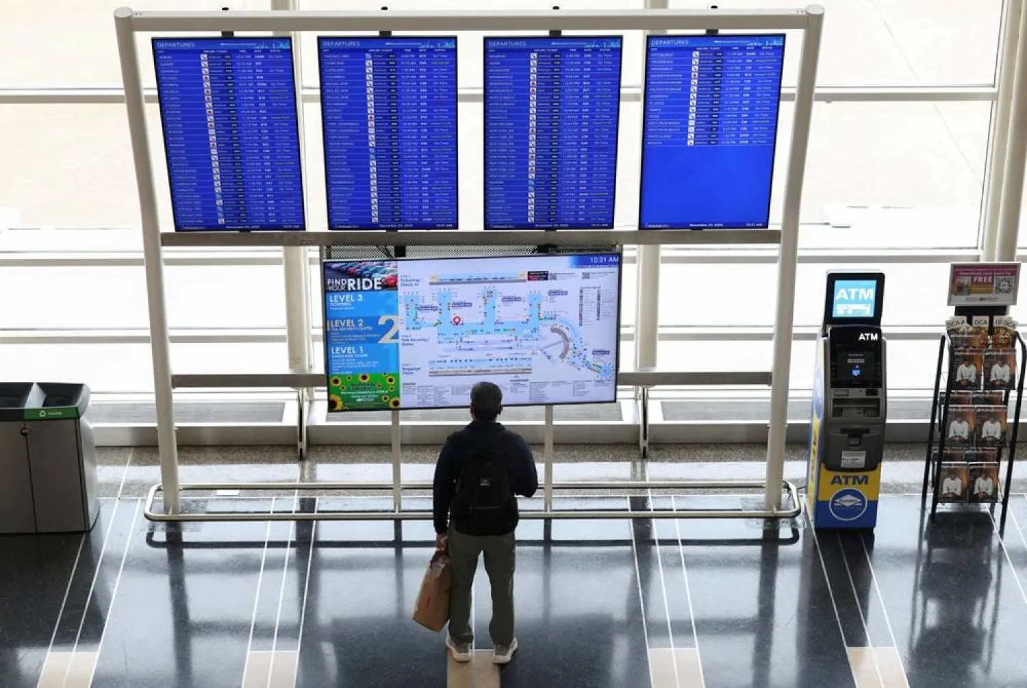 A passenger looks up at a flight information board on the busiest travel day of the Thanksgiving holiday, at Ronald Reagan Washington National Airport in Arlington, Virginia, US, November 25, 2025. (Reuters)