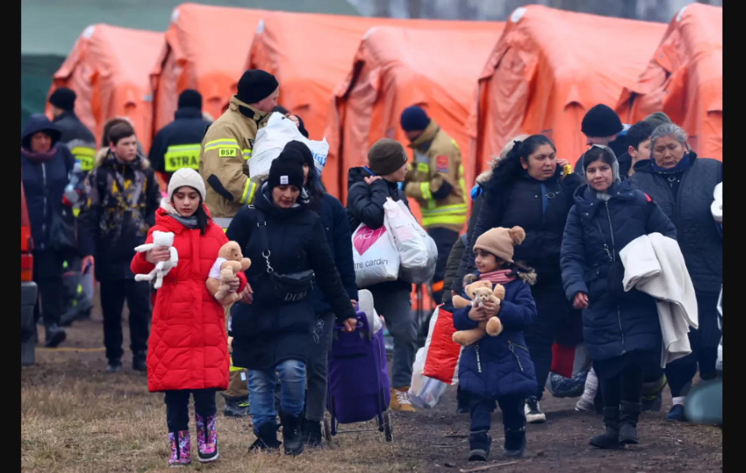 أشخاص يمرون بجوار الخيام في طريقهم للصعود إلى القطار بعد عبورهم الحدود من أوكرانيا إلى بولندا وسط الغزو الروسي (رويترز)
