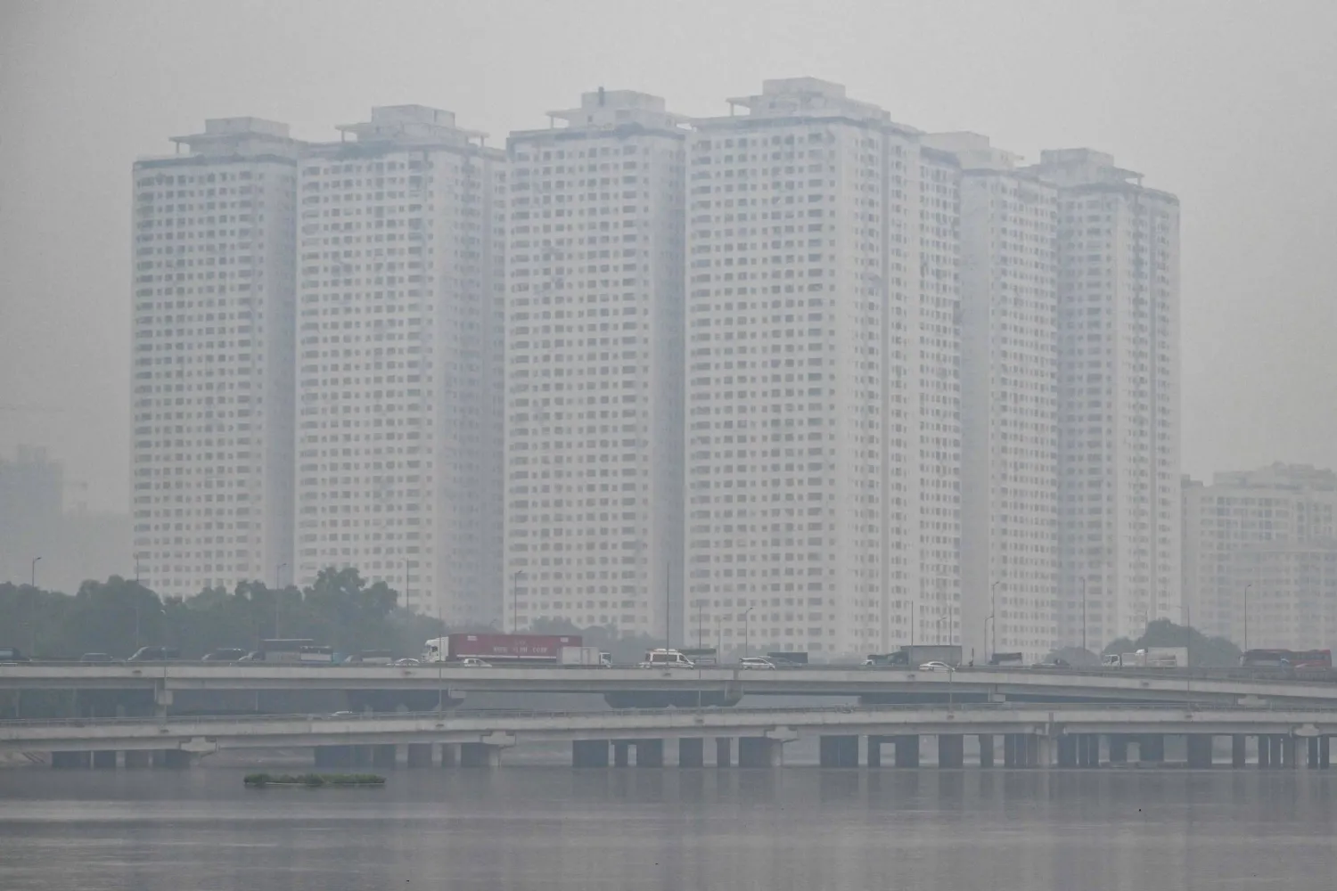 This picture shows vehicles driving on a highway amid heavy air pollution conditions in Hanoi on December 11, 2025. (Photo by NHAC NGUYEN / AFP)