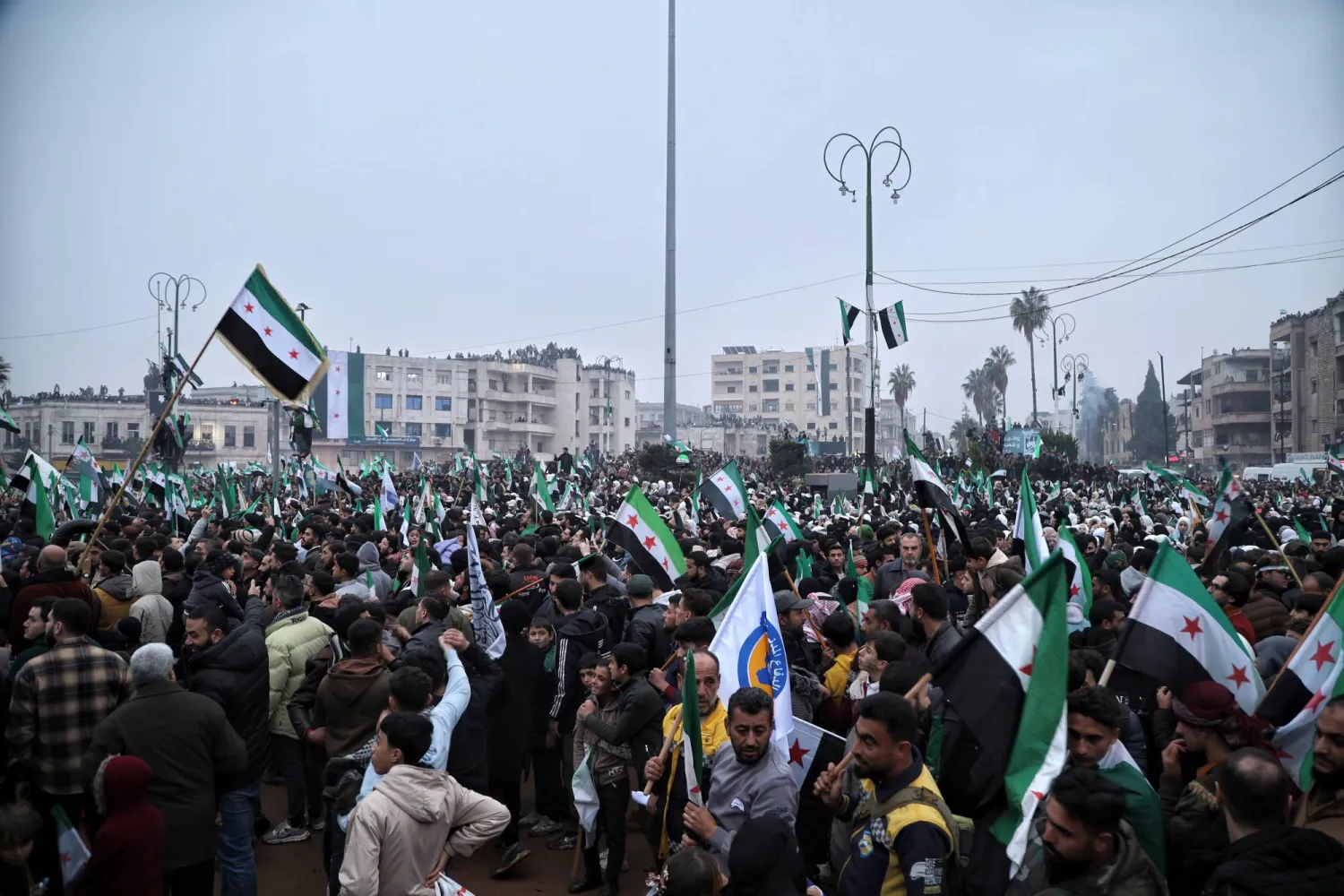 تجمع الناس خلال مسيرة إحياءً للذكرى السنوية الأولى للإطاحة بنظام بشار الأسد في إدلب (إ.ب.أ)