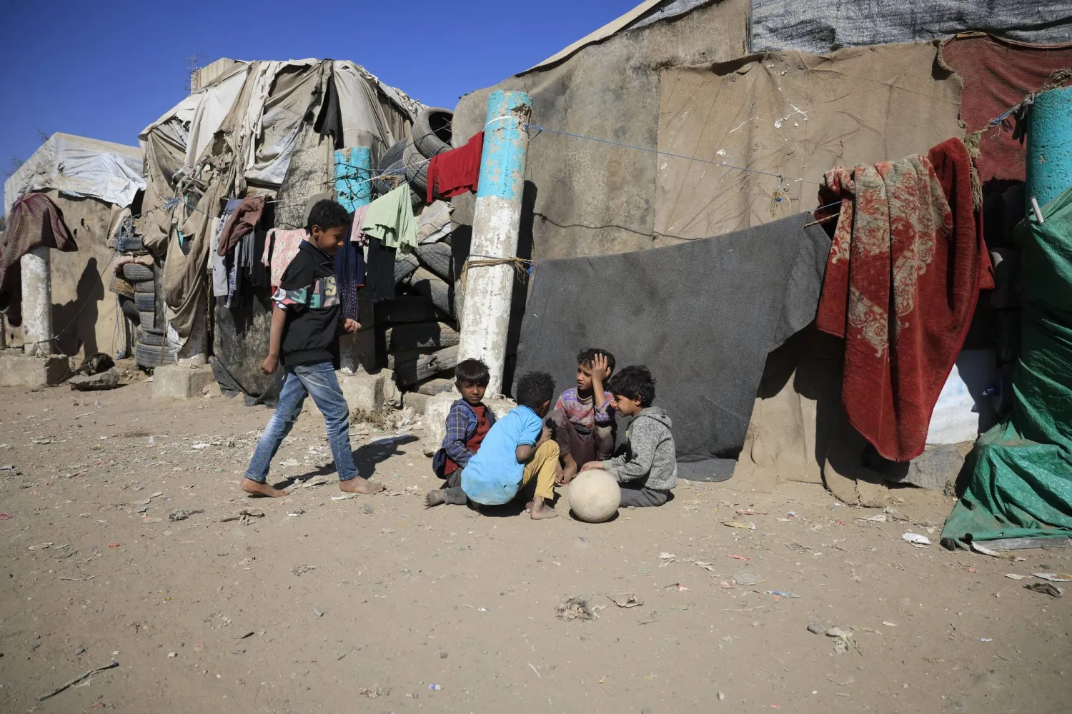 مجموعة من الصبية النازحين يتجمعون داخل مخيم مؤقت وسط طقس بارد في صنعاء (إ.ب.أ)