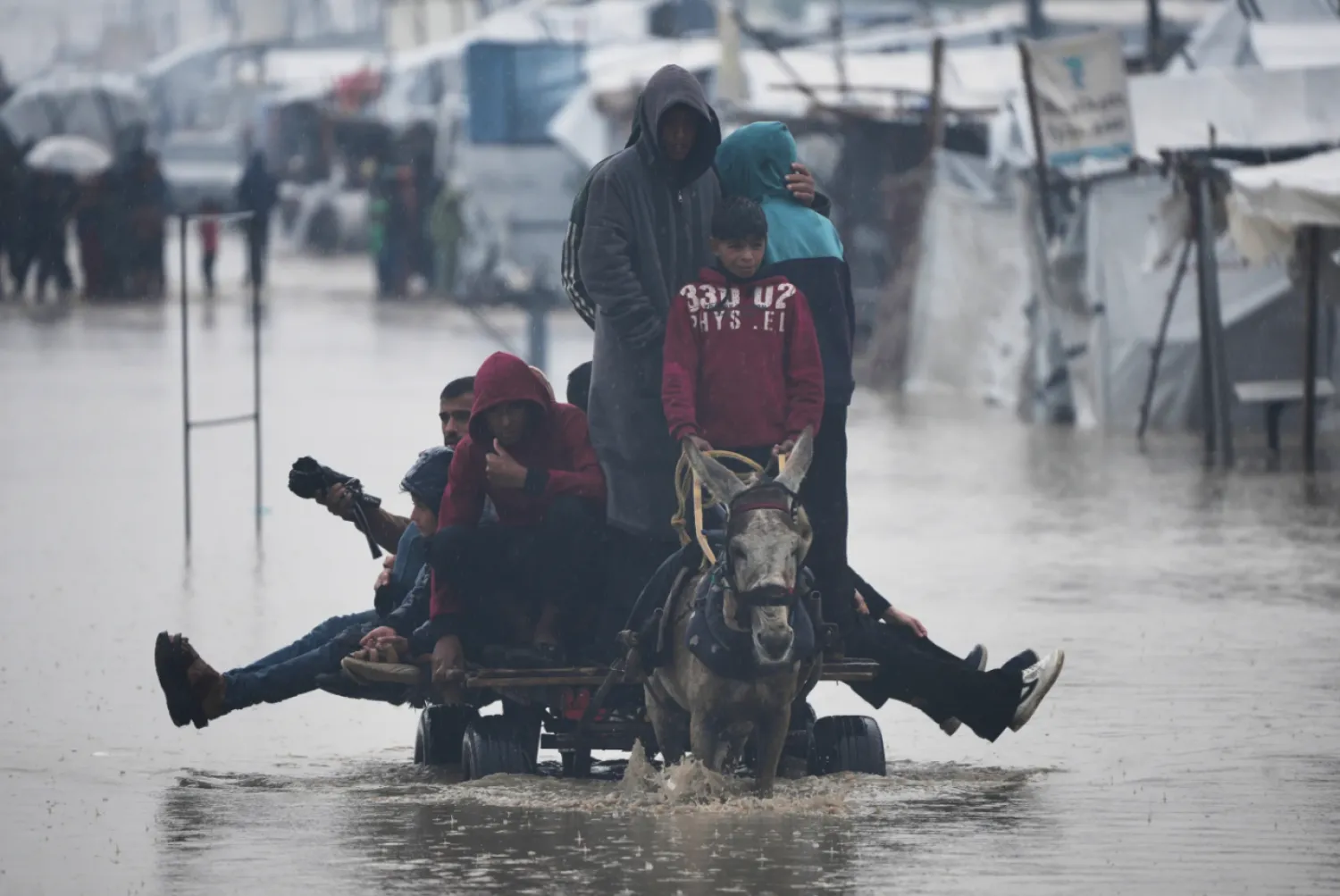 Palestinians cross a flooded street following heavy rain in Khan Younis, southern Gaza Strip, Thursday, Dec. 11, 2025. (AP Photo/Abdel Kareem Hana)