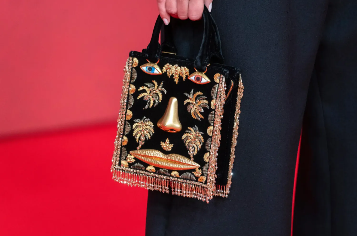 An actress holds a Schiaparelli purse while posing for a photo on the red carpet during 22nd Marrakech Film Festival, in Morocco, Tuesday, Dec. 2, 2025. (AP Photo/Mosa’ab Elshamy)

