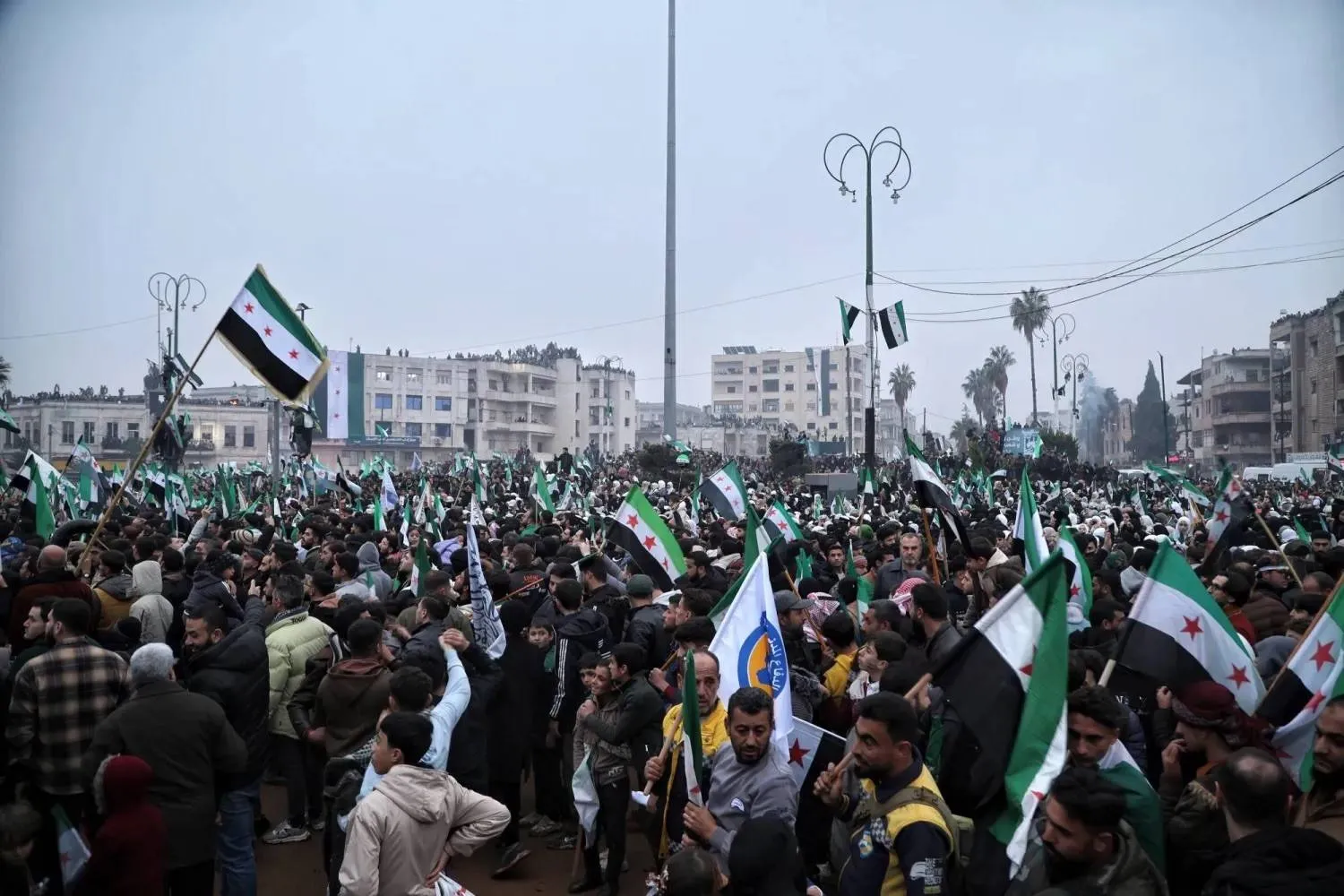 People gather during a march marking the first anniversary of the overthrow of Bashar al-Assad’s regime in Idlib (EPA)