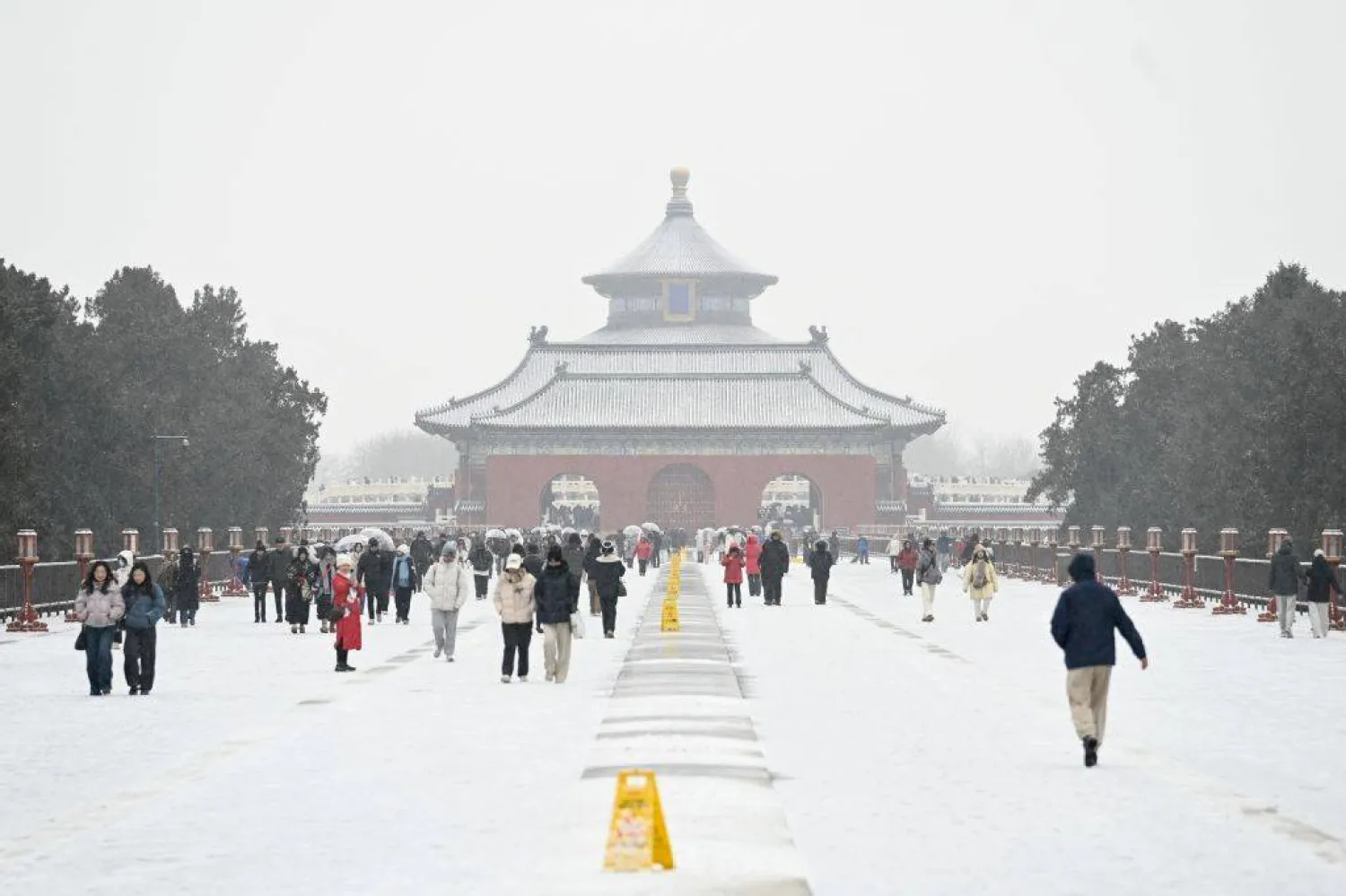 صينيون وسط الثلوج بأحد المزارات الدينية القديمة في بكين (أ.ف.ب)