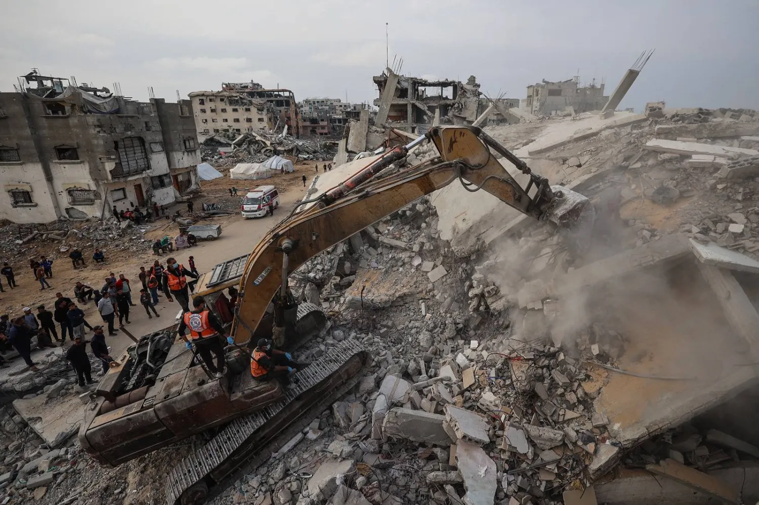 يستخدم أفراد الدفاع المدني حفارة للبحث عن رفات الضحايا في أنقاض مبنى مدمر في مخيم البريج للاجئين (أ.ف.ب)