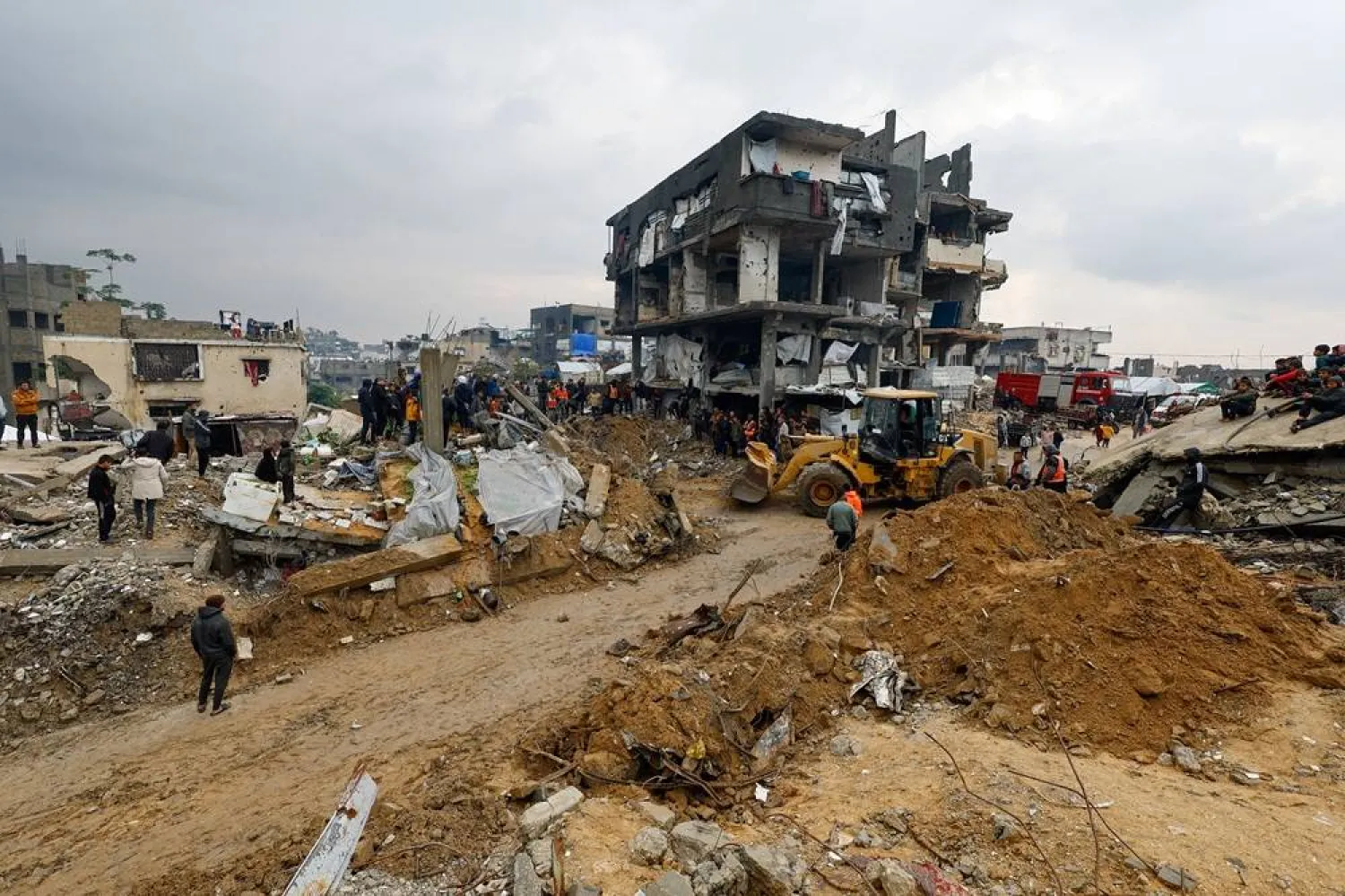 Heavy machinery operates as Palestinians gather amid a search for victims in a destroyed house that collapsed due to heavy rains, in Beit Lahia, in the northern Gaza Strip, December 12, 2025. (Reuters) 