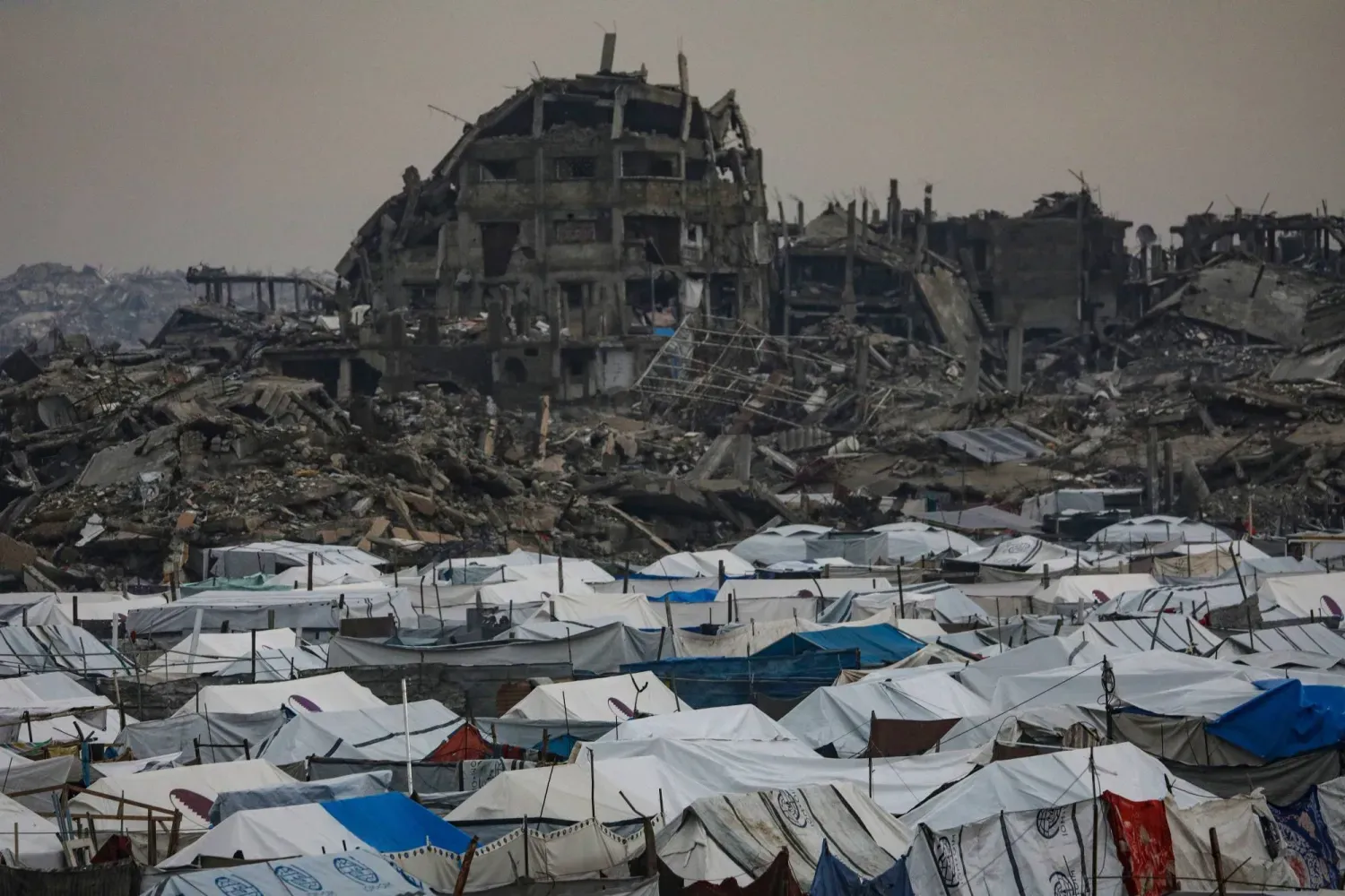 Gazze şehrinin doğusundaki Zeytun mahallesinde, arkalarında yıkılmış binaların görüldüğü Filistinli mülteci çadırları (EPA)
