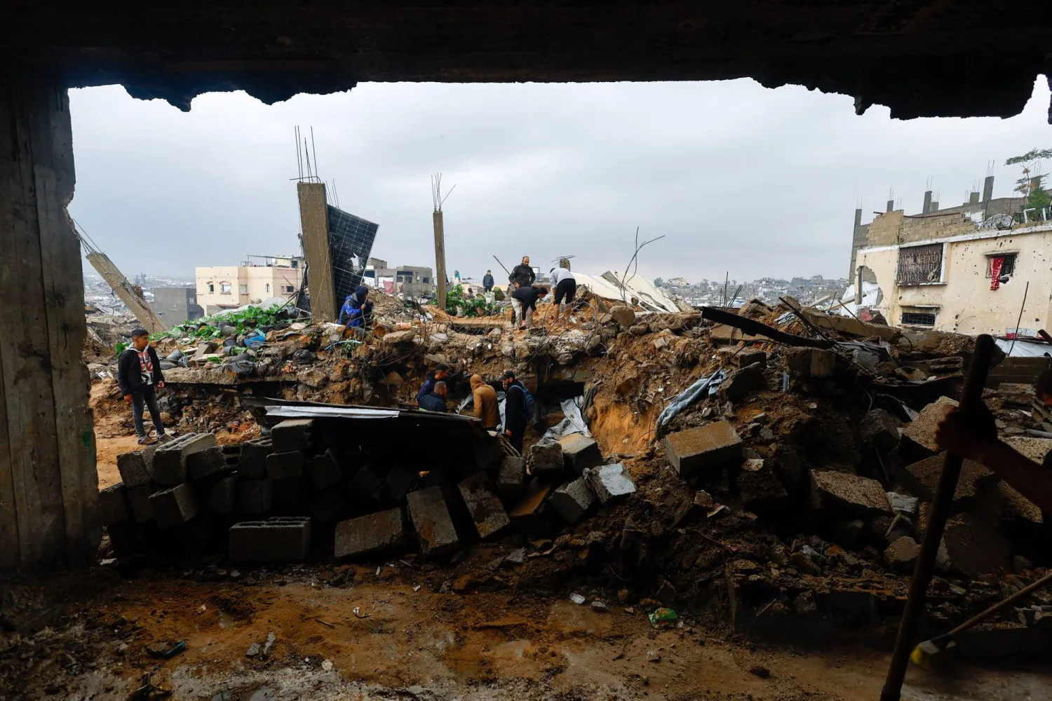 فلسطينيون يبحثون عن ضحايا جراء انهيار منزل متضرر من القصف الإسرائيلي على قطاع غزة (رويترز) 