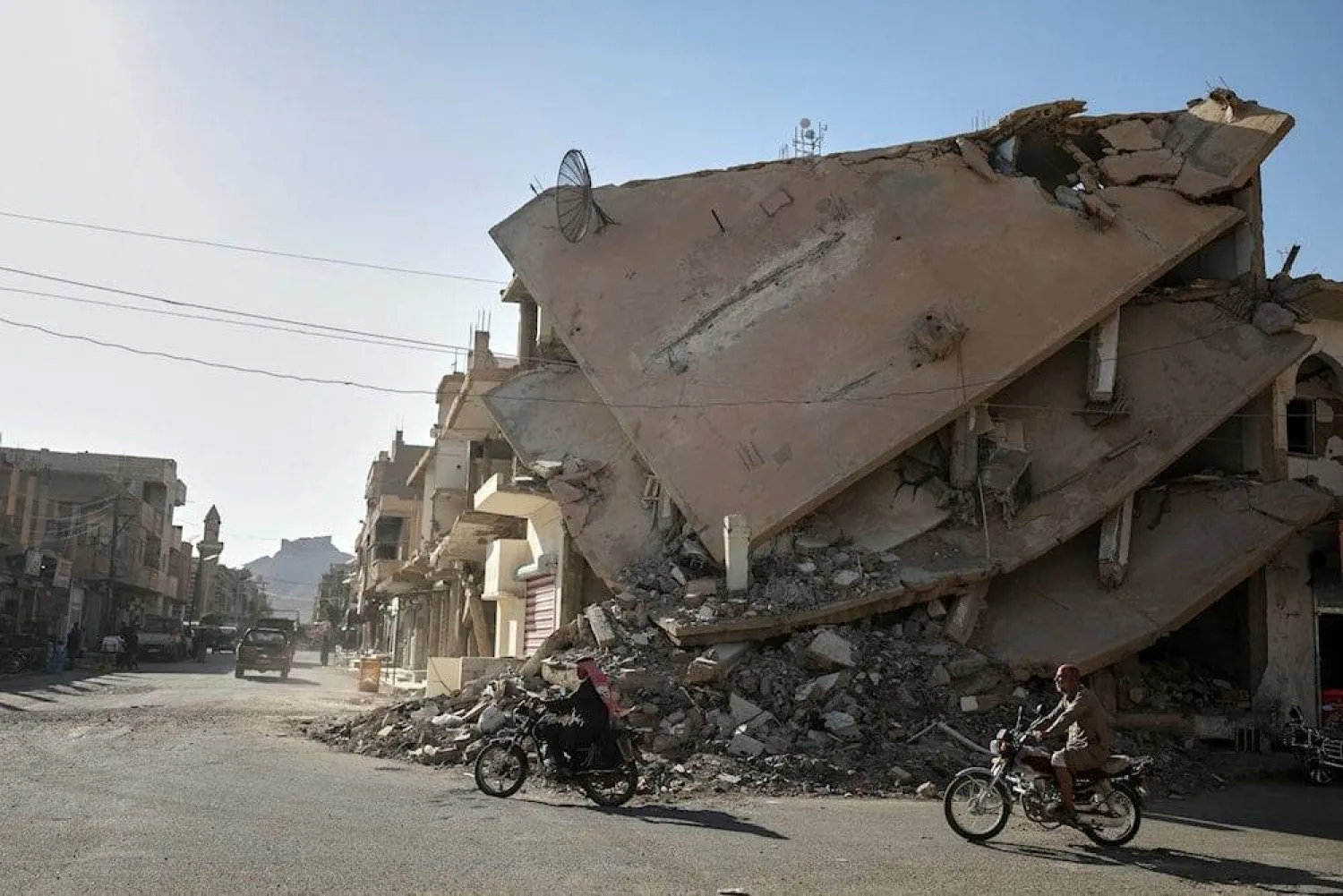 Residents ride a motorcycle along a war-damaged street in Palmyra, Syria. (AP)