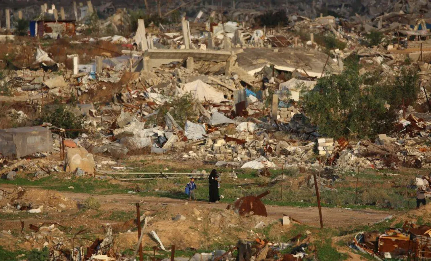 Gazze Şeridi'nin orta kesimlerindeki Nuseyrat Mülteci Kampı’nda savaşın yol açtığı yıkımın ortasında yürüyen Filistinli bir kadın (AFP)