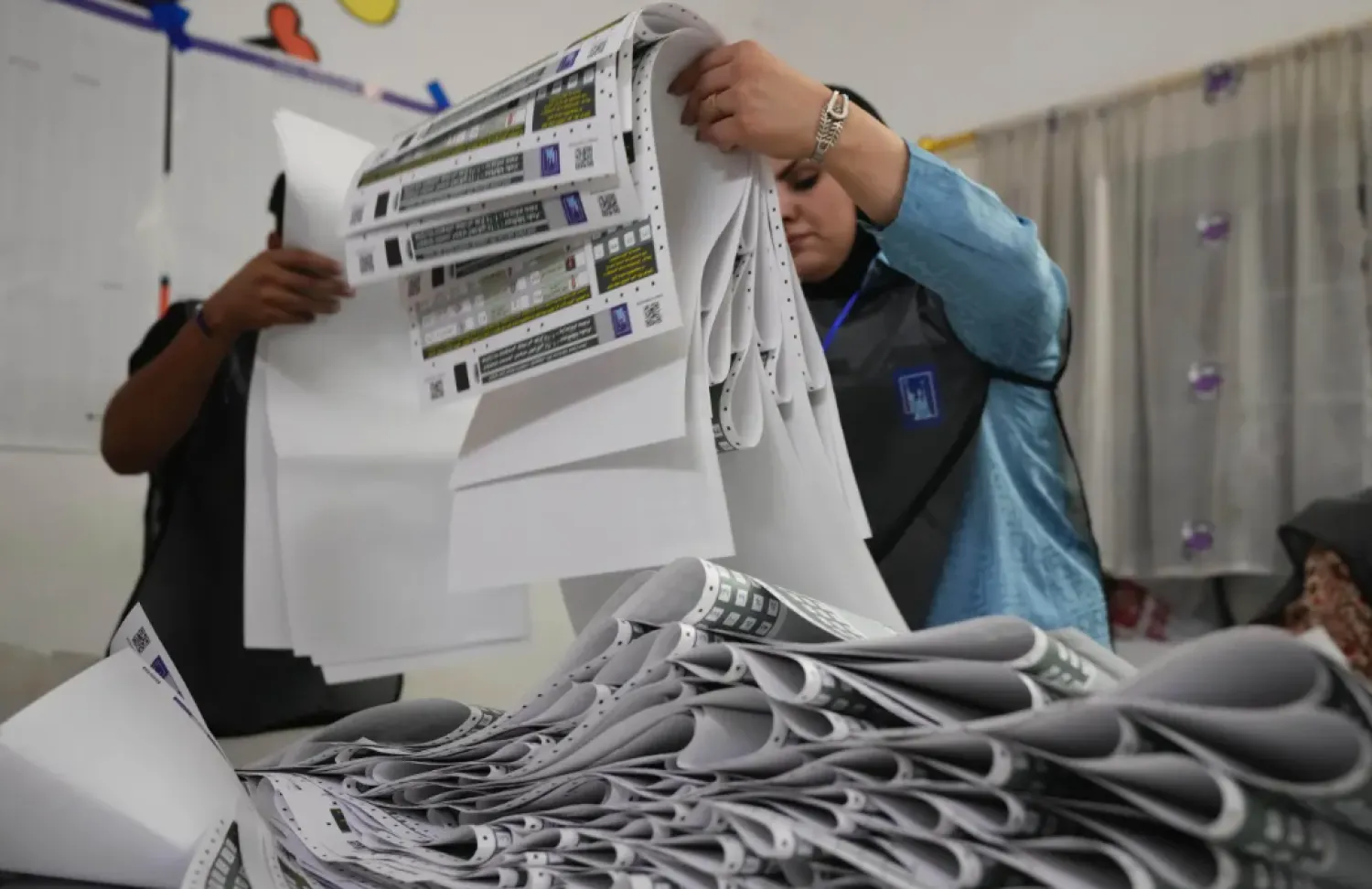 Election workers gather parliamentary election ballots after the polls closed in Baghdad, Iraq, Nov. 11, 2025. (AP Photo/Hadi Mizban, File)