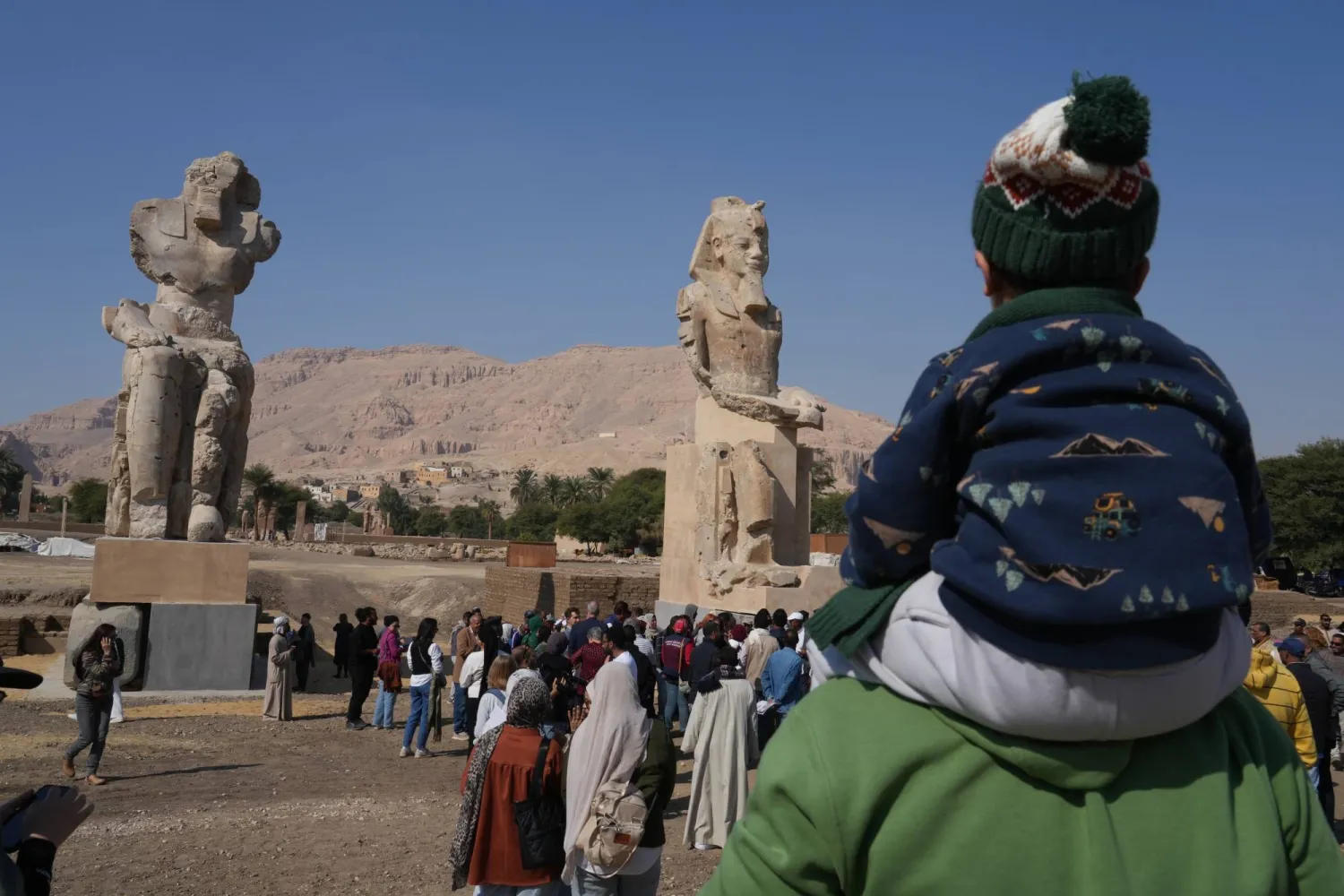 Visitors watch the two giant reassembled alabaster statues of Pharoah Amenhotep III, in the southern city of Luxor, Egypt, Sunday, Dec. 14, 2025. (AP Photo/Amr Nabil)