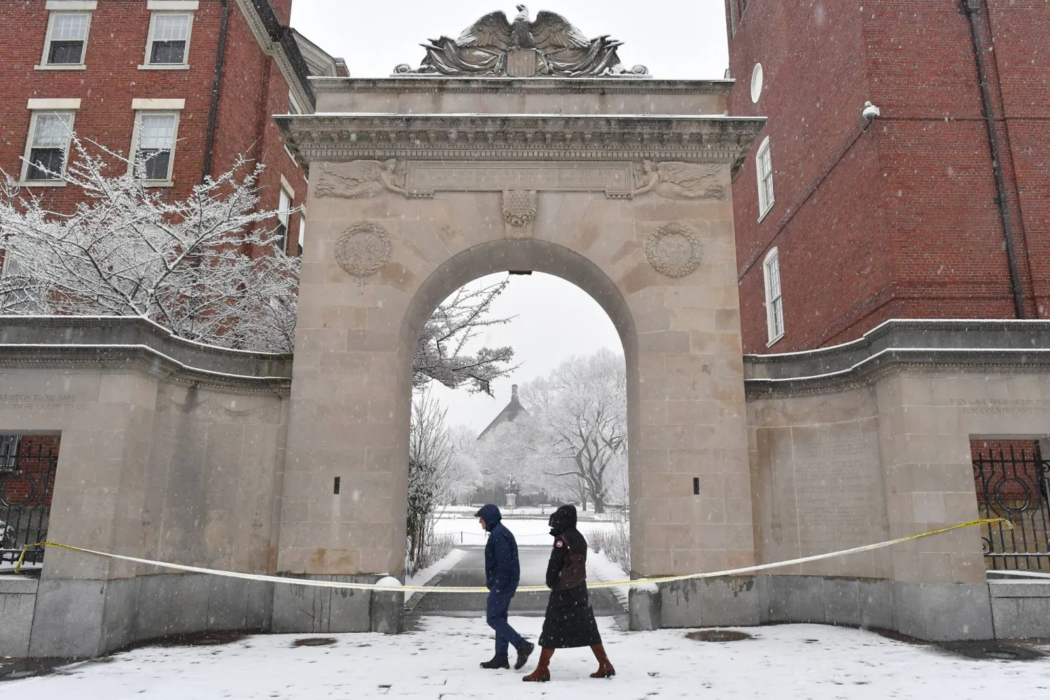 Passers-by walk past crime scene tape at an entrance to Brown University, Sunday, Dec. 14, 2025, in Providence, R.I., following the Saturday, Dec. 13, shooting at the university. (AP Photo/Steven Senne)