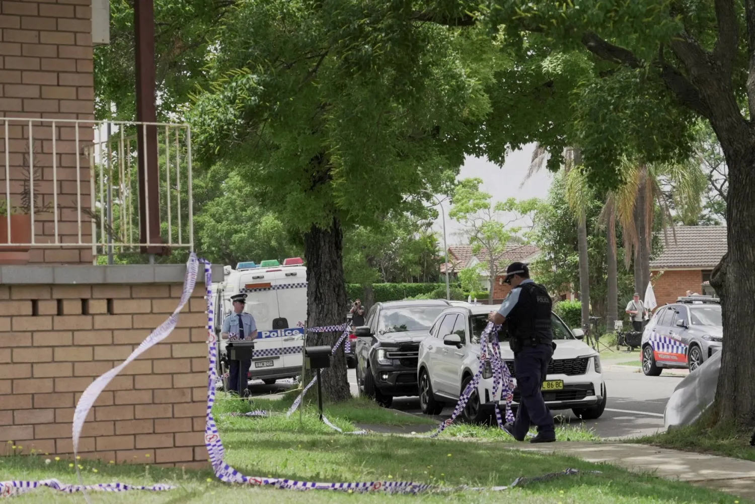 شرطي أسترالي يزيل شريطاً بلاستيكياً يمنع الاقتراب من منزل أحد المشتبه بهم في هجوم م شاطئ بوندي (رويترز)