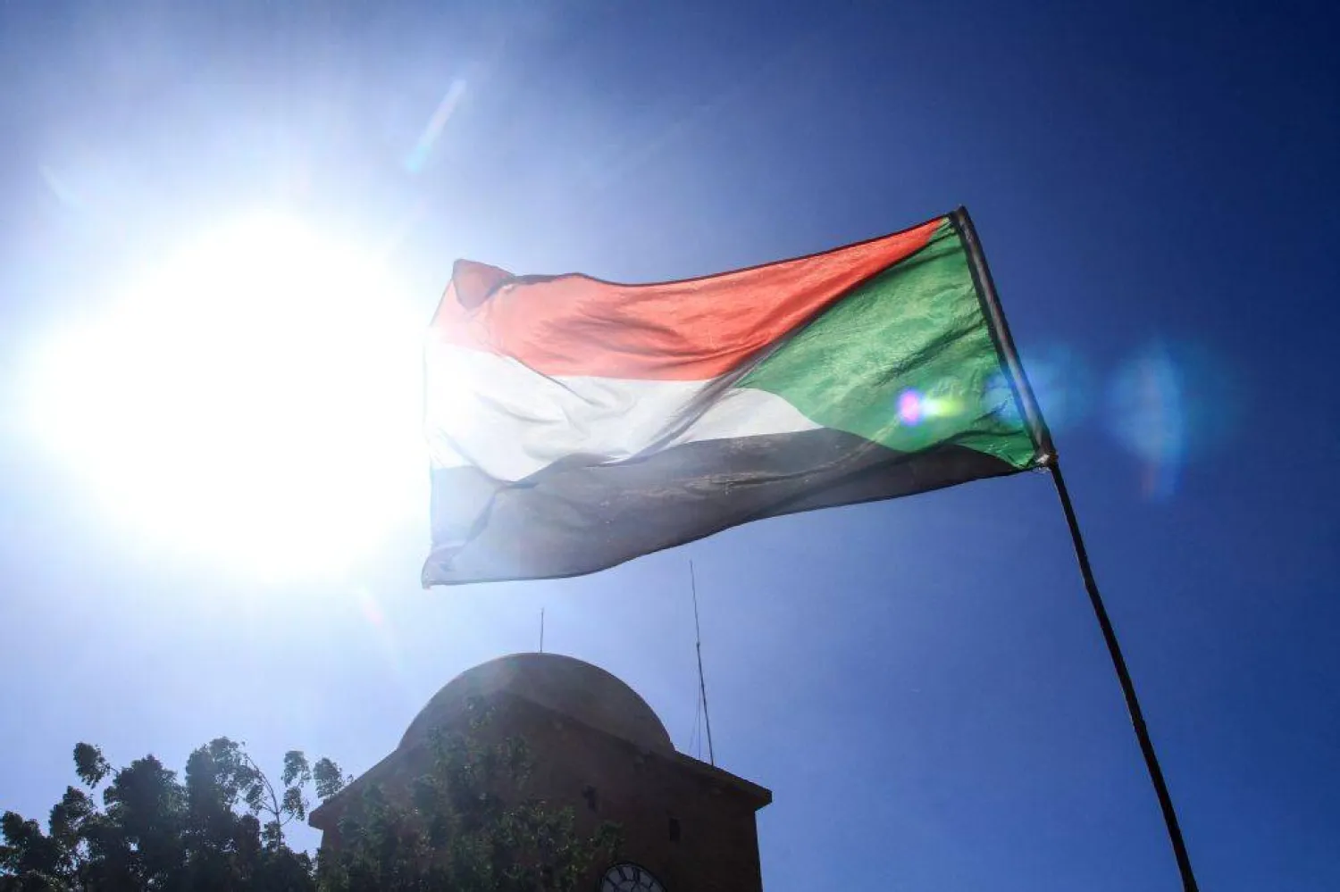 The Sudanese flag flutters in Omdurman, part of greater Khartoum on December 13, 2025. Since April 2023 war has raged between the Sudanese regular army and the paramilitary Rapid Support Forces (RSF), killing tens of thousands of people and created one of the world's worst humanitarian crises. (Photo by Ebrahim Hamid / AFP)