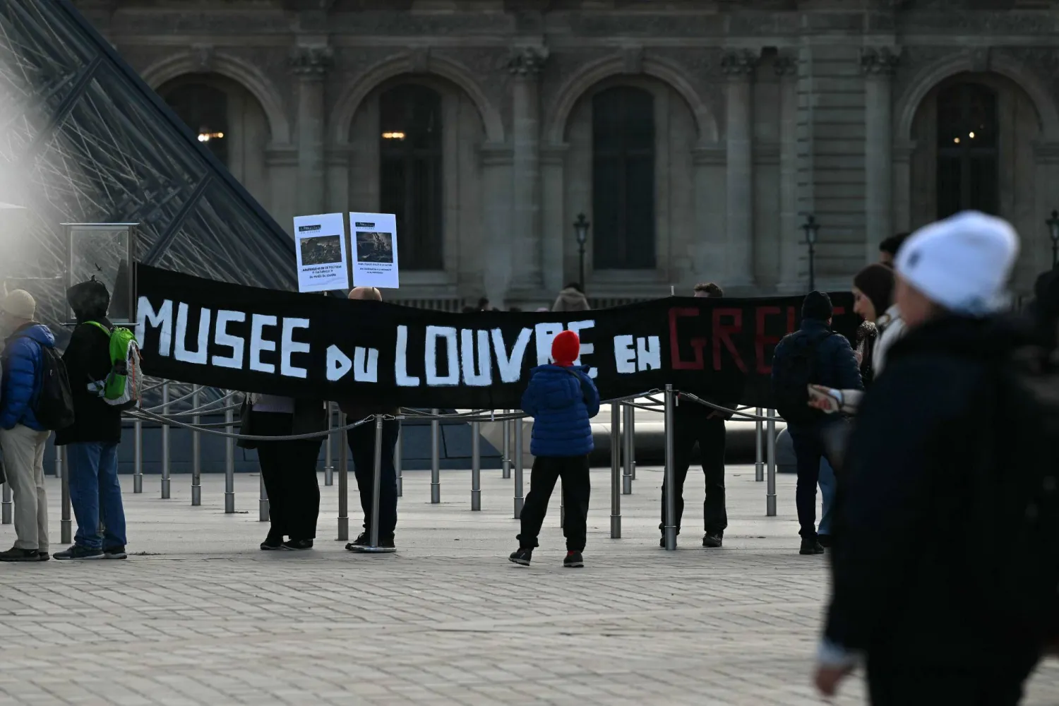 This photograph shows a banner which reads "Louvre Museum on Strike" outside the entrance to the Louvre as museum workers voted to go on strike against increasingly deteriorating working conditions and the declining visitor experience at the world famous museum, in Paris on December 15, 2025. (AFP)